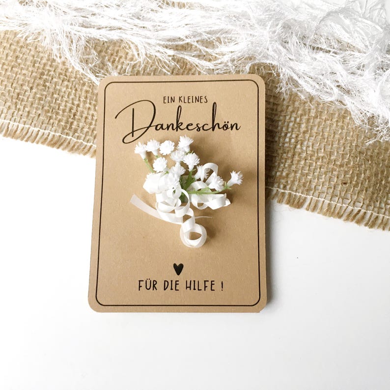 May include: A brown card with white flowers and a white ribbon. The card says "Ein kleines Dankesch&ouml;n" and "F&uuml;r die Hilfe!" with a small heart symbol.
