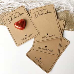 May include: Four brown cardstock gift tags with the text "Ein kleines Dankesch&ouml;n" and different messages of thanks. The top tag has a small red heart-shaped chocolate on it.