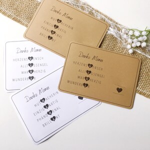 May include: Four brown cards with white text and black hearts. The text on the cards reads "Danke Mama" and lists positive adjectives describing a mother.