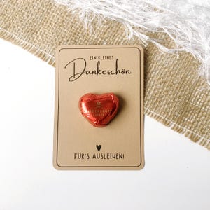 May include: A small brown card with the text "Ein kleines Dankesch&ouml;n" and "F&uuml;r's Ausleihen!"  A heart-shaped chocolate is attached to the card.
