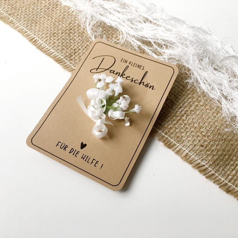 May include: A small brown card with white flowers and a white ribbon. The card says "Ein kleines Dankesch&ouml;n" and "F&uuml;r die Hilfe!"