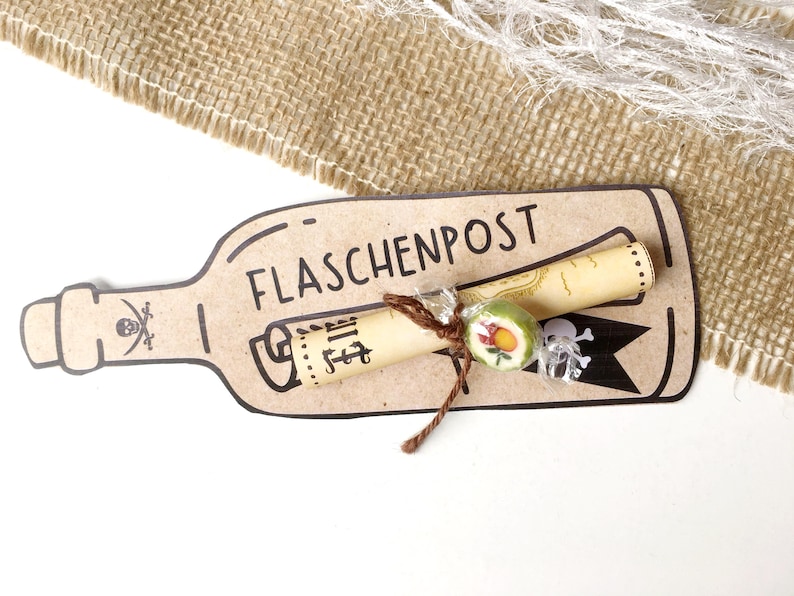 May include: A brown paper bottle with a rolled up scroll inside. The bottle has the text "FLASCHENPOST" written on it. The scroll is tied with twine and has a small candy on it.
