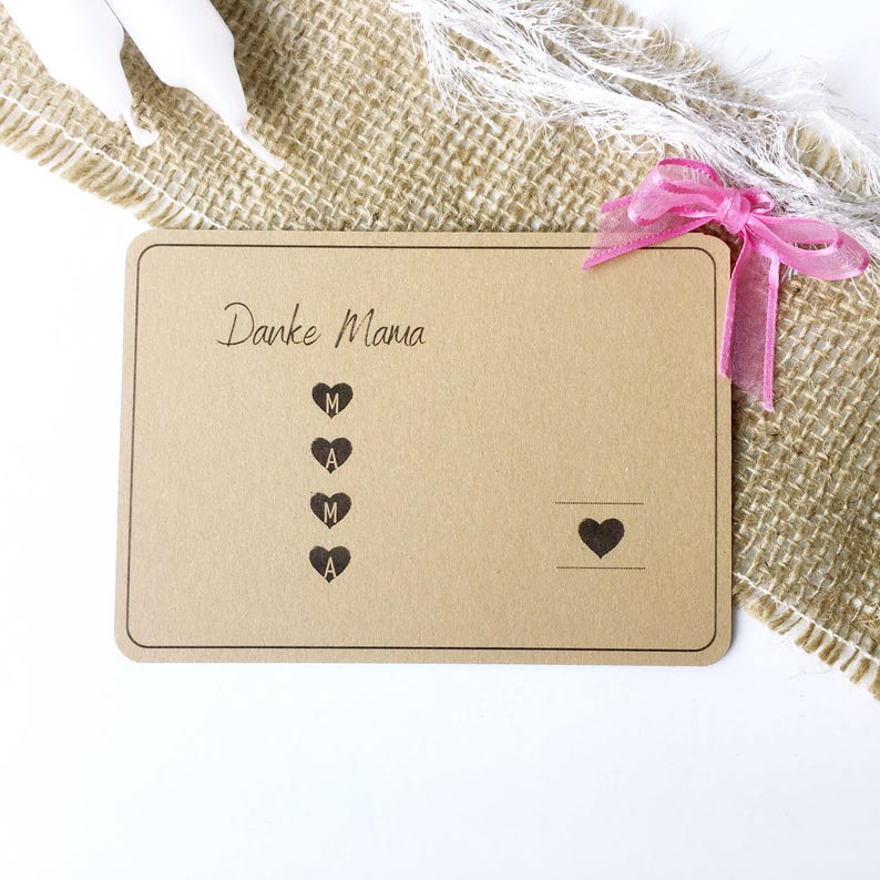 May include: A brown card with the text "Danke Mama" and a vertical row of hearts with the letters "MAMA" inside. A single heart is on the right side of the card.