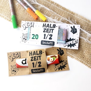 Può includere: Due biglietti regalo fatti a mano con il testo "HALB-ZEIT 1/2 Geschafft!" e "YES! SUPER!". Un biglietto contiene una banconota da 20 euro, l'altro una barretta di cioccolato. I pennarelli sono sullo sfondo.