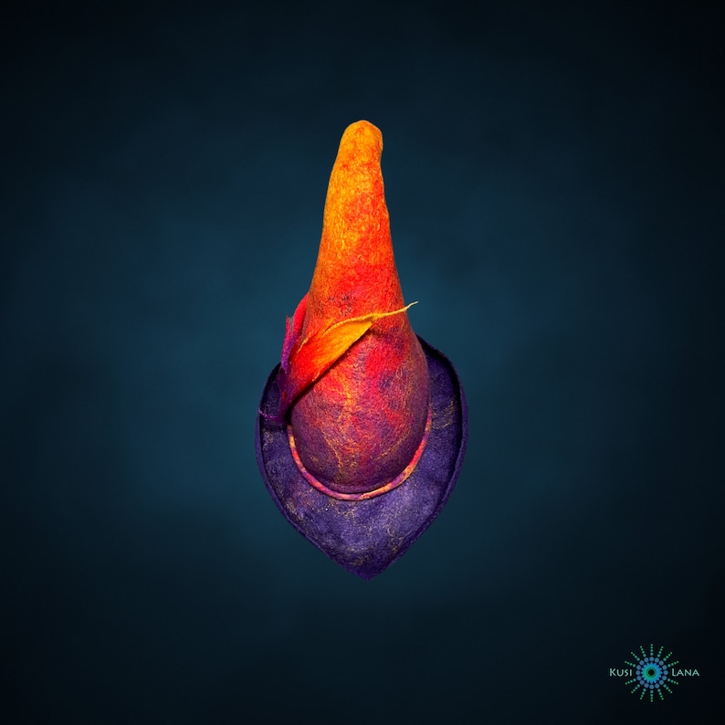 May include: A tall, pointed hat made of felt with a purple brim and a bright orange and yellow top. The hat is decorated with a small, orange felt feather.