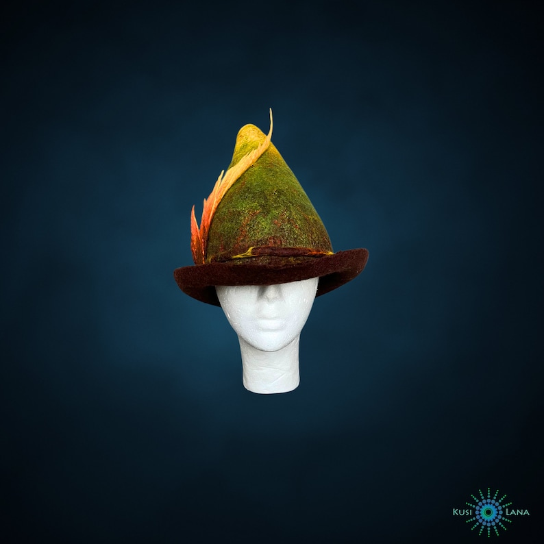 May include: A green and brown felt hat with a yellow and orange feather. The hat is on a white mannequin head.