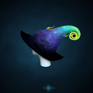 May include: A blue and green felt witch hat with a curled brim and a yellow accent. The hat is on a white mannequin head.