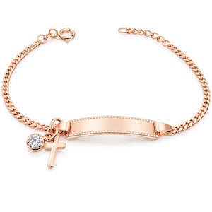 Könnte beinhalten: Ein roségoldfarbenes Kettenarmband mit einer zentralen, rechteckigen Identifikationsplatte mit Perlenrand. Das Armband enthält einen Anhänger mit einem einzelnen klaren, runden Edelstein und einen kleinen, schlichten Kreuzanhänger.