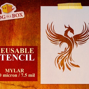 May include: Reusable stencil made of 190 micron Mylar, featuring a detailed design of a phoenix with outstretched wings. The stencil is white and is shown against a brown wooden background.