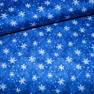 Könnte beinhalten: Blauer Stoff mit einem weißen Schneeflockenmuster. Der Stoff ist in der Mitte gefaltet, sodass das Muster auf beiden Seiten sichtbar ist.