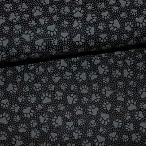 Könnte beinhalten: Schwarzer Stoff mit einem sich wiederholenden Muster aus grauen Pfotenabdrücken.