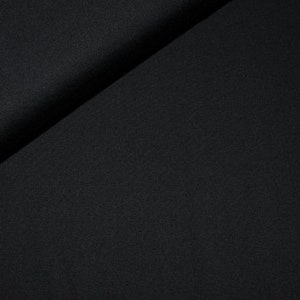 Könnte beinhalten: Nahaufnahme eines schwarzen Stoffes mit glatter, gleichmäßiger Textur. Der Stoff ist in der Mitte gefaltet, wodurch eine diagonale Linie über das Bild verläuft.