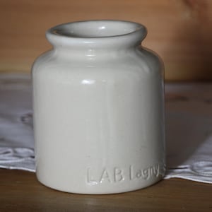 Può includere: Un barattolo di ceramica bianco con la scritta "LAB Lagny" sul fondo.