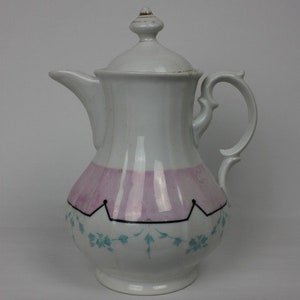 Könnte beinhalten: Eine weiße Porzellan-Teekanne mit einem rosa-blauen Blumendesign. Die Teekanne hat einen Deckel mit einem Knopf oben und einen Griff an der Seite.