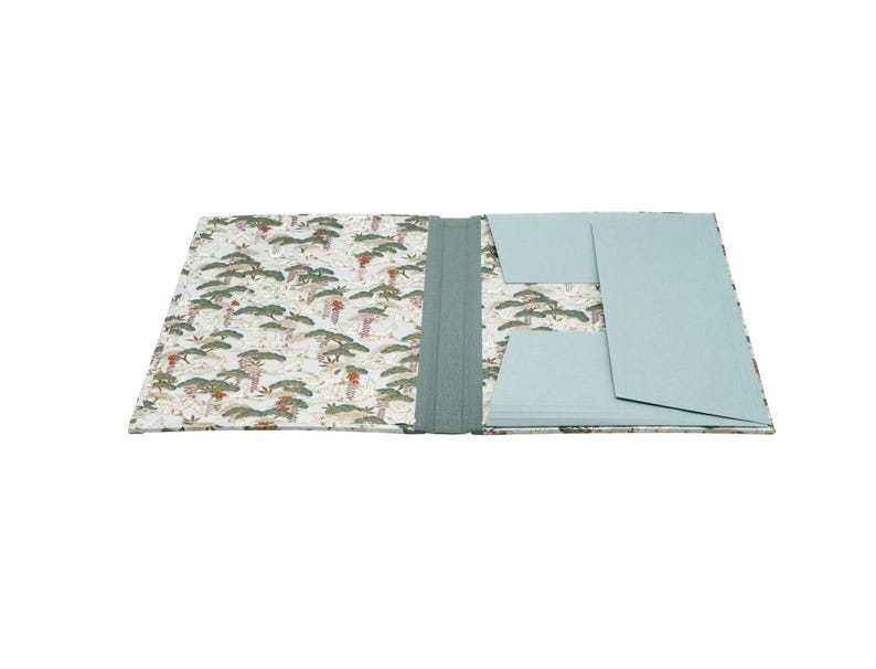 Handgefertigte Sammelmappe mit Japanpapier bezogen und mit strapazierfähigem Bucheinbandgewebe eingefasst. Im Inneren schützen drei eingearbeitete Klappen den Inhalt zuverlässig vor dem Herausfallen. Ein Gummizugband hält die Mappe sicher verschlossen. Ideal für Zeichnungen, Dokumente, Briefe und andere kreative Arbeiten. Es besteht die Möglichkeit zur Personalisierung.