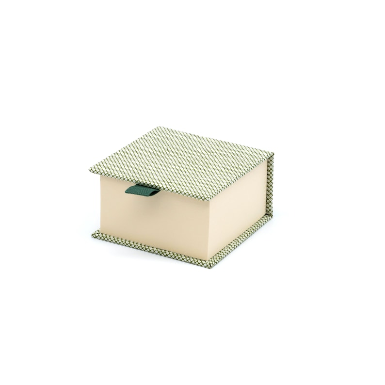 Op de afbeelding: Een klein, vierkant doosje met een groen-wit gepatroneerd deksel en een cr&egrave;mekleurige basis. Het doosje heeft een groene linttrekker.