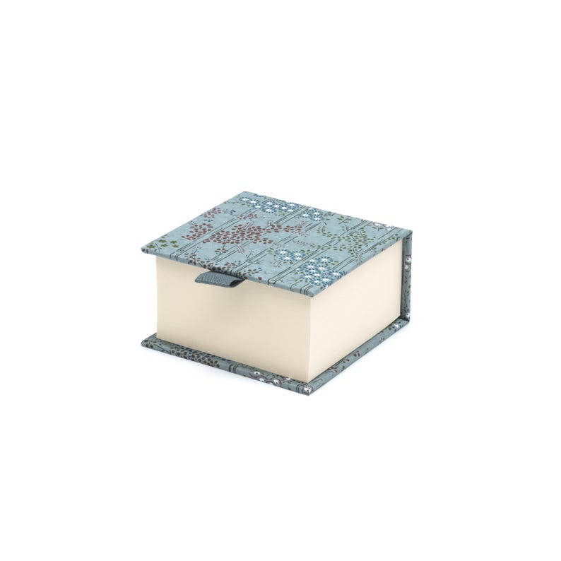 Op de afbeelding: Een kleine, vierkante doos met een lichtblauw bloemenpatroon op de deksel. De doos heeft een cr&egrave;mekleurige binnenkant en een grijs lint.