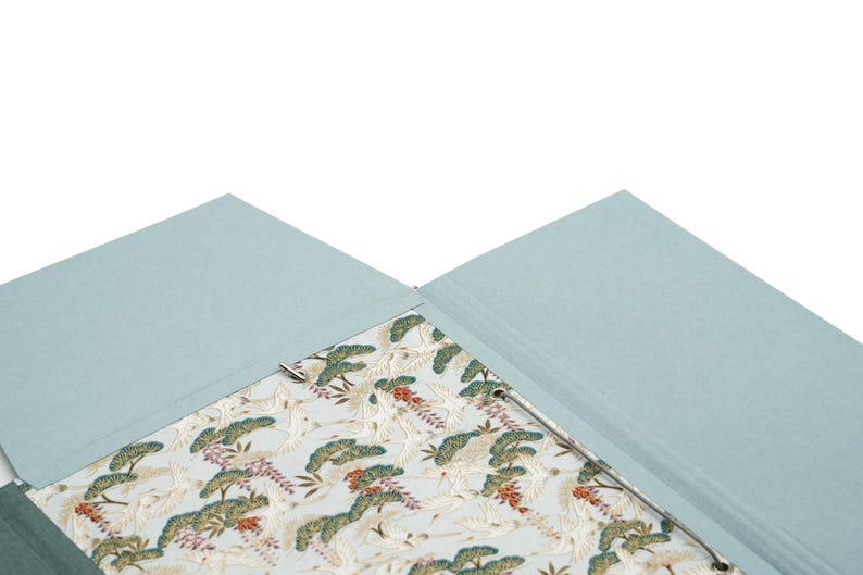 Handgefertigte Sammelmappe mit Japanpapier bezogen und mit strapazierfähigem Bucheinbandgewebe eingefasst. Im Inneren schützen drei eingearbeitete Klappen den Inhalt zuverlässig vor dem Herausfallen. Ein Gummizugband hält die Mappe sicher verschlossen. Ideal für Zeichnungen, Dokumente, Briefe und andere kreative Arbeiten. Es besteht die Möglichkeit zur Personalisierung.