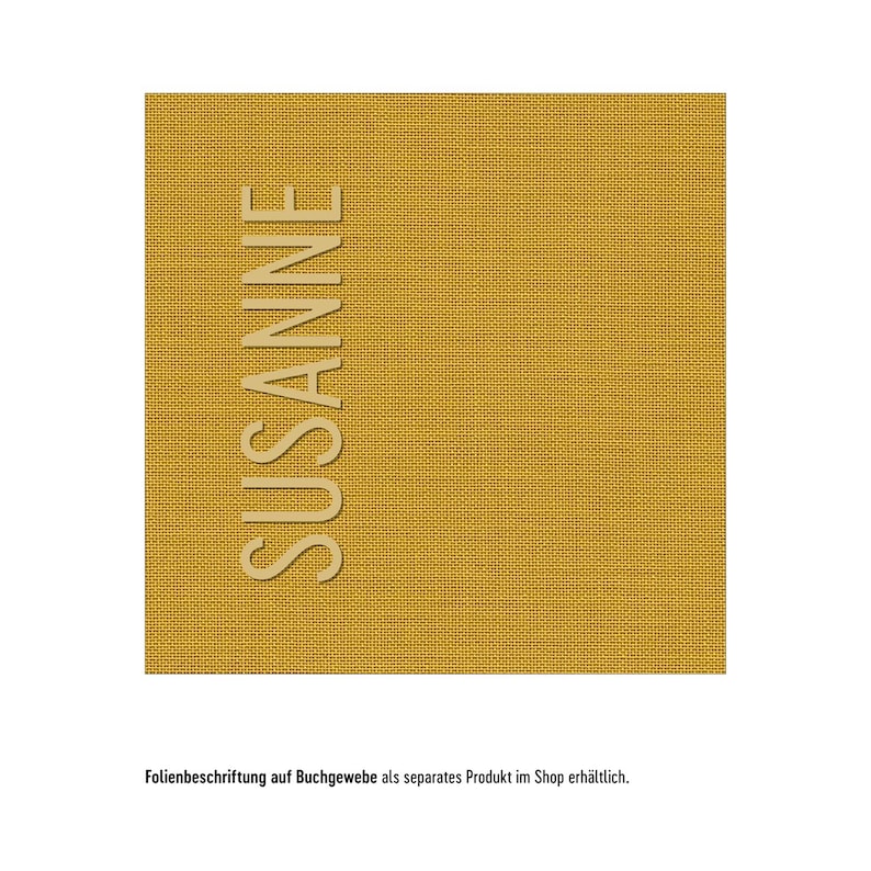 K&ouml;nnte beinhalten: Ein quadratisches St&uuml;ck buchbinderleinen in Senfgelb mit einer sichtbaren Webstruktur. Der Name SUSANNE ist vertikal in einer hellbeigen serifenlosen Schrift auf der linken Seite des Stoffes aufgedruckt. Der Text ist klar lesbar.