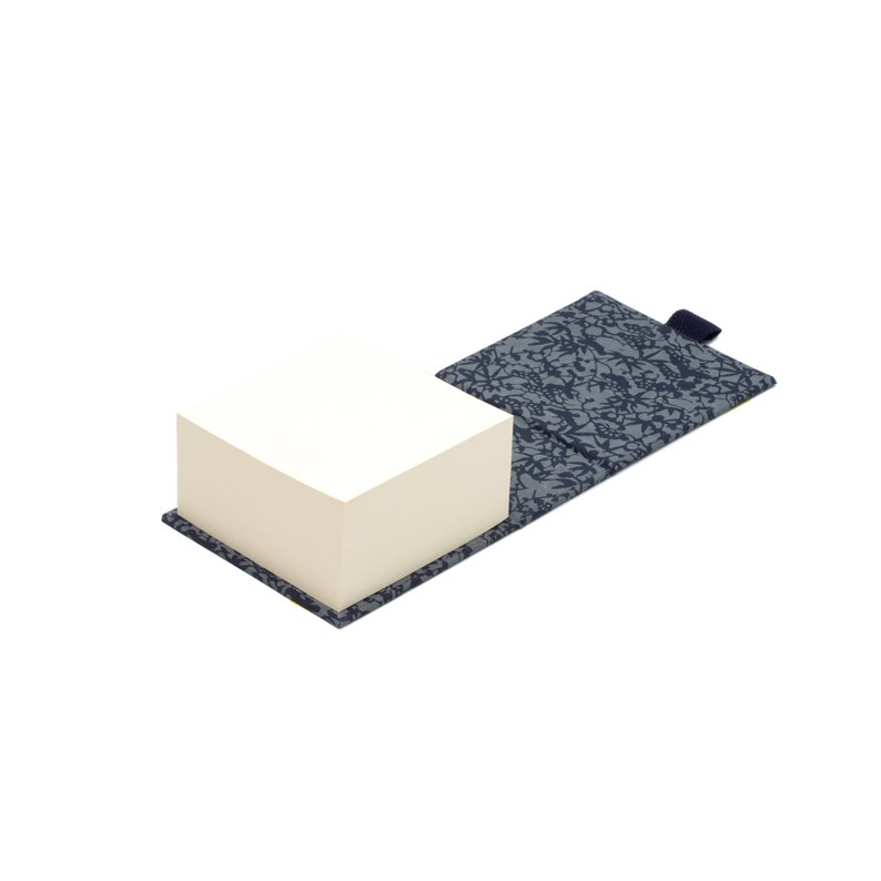 May include: A stack of white notepaper in a blue and white patterned cover with a blue tab.