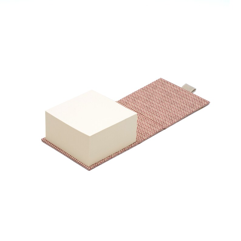 May include: A red and white patterned fabric notepad holder with a stack of blank white sticky notes inside.