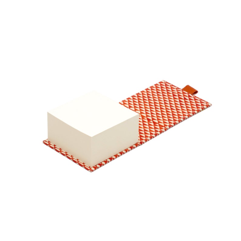 May include: A white notepad with a red and white geometric patterned cover. The notepad is open and the cover is folded back.