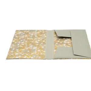 Handgefertigte Sammelmappe mit Japanpapier bezogen und mit strapazierfähigem Bucheinbandgewebe eingefasst. Im Inneren schützen drei eingearbeitete Klappen den Inhalt zuverlässig vor dem Herausfallen. Ein Gummizugband hält die Mappe sicher verschlossen. Ideal für Zeichnungen, Dokumente, Briefe und andere kreative Arbeiten. Es besteht die Möglichkeit zur Personalisierung.