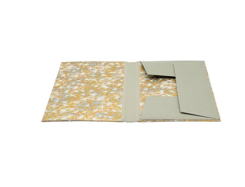 Handgefertigte Sammelmappe mit Japanpapier bezogen und mit strapazierfähigem Bucheinbandgewebe eingefasst. Im Inneren schützen drei eingearbeitete Klappen den Inhalt zuverlässig vor dem Herausfallen. Ein Gummizugband hält die Mappe sicher verschlossen. Ideal für Zeichnungen, Dokumente, Briefe und andere kreative Arbeiten. Es besteht die Möglichkeit zur Personalisierung.