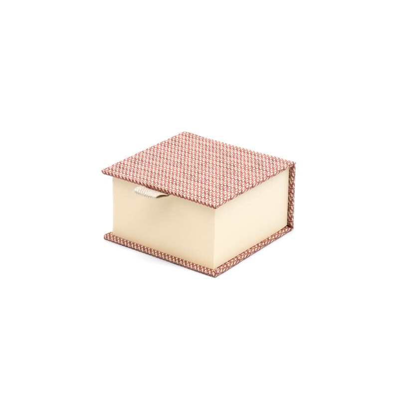 May include: A small, square box with a red and white patterned lid and a cream-colored base. The lid has a white pull tab.