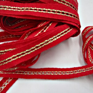 Könnte beinhalten: Rotes Band mit goldener Einfassung, mit gewebter Textur. Das Band hat einen goldenen Metallic-Faden, der entlang der Kanten verläuft.