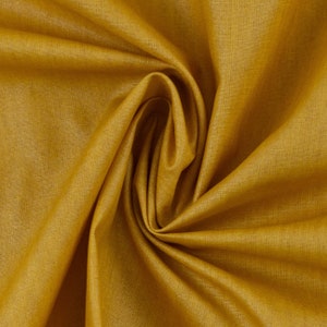 Könnte beinhalten: Nahaufnahme eines glatten, goldgelben Stoffes mit einer dezenten Textur. Der Stoff ist gefaltet und drapiert und zeigt seine weiche und fließende Beschaffenheit.