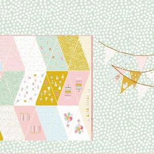 Könnte beinhalten: Ein grüner Hintergrund mit weißen Punkten zeigt eine Patchwork-Decke mit verschiedenen Mustern in Rosa, Blau, Gelb und Weiß. Die Decke besteht aus Dreiecken und hat ein Geburtstagsthema mit Bildern von Kuchen, Ballons und Kerzen. Zwei Girlanden mit dreieckigen Fahnen in verschiedenen Farben und Mustern hängen rechts im Bild.