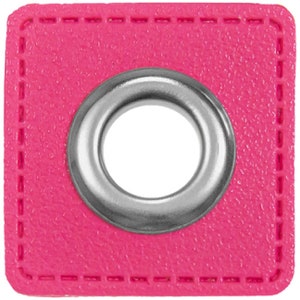 May include: A pink square fabric grommet with a silver metal ring in the center.