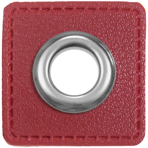 May include: A red square-shaped leather patch with a silver metal grommet in the center.