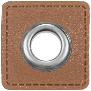 Op de afbeelding: Een vierkant van bruin leer met een zilveren metalen oogje in het midden. Het oogje heeft een rond gat in het midden.