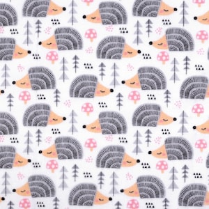 Op de afbeelding: Een witte stof met een herhalend patroon van grijze egels met roze neuzen en roze paddenstoelen. De egels slapen en hebben hun ogen dicht. De achtergrond is wit met grijze en zwarte geometrische vormen.