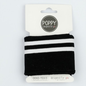 Może przedstawiać: Czarna dzianinowa mankieta z dwoma białymi paskami. Mankiet jest zapakowany na białej kartce z tekstem "POPPY designed for you" i "OEKO-TEX® CONFIDENCE IN TEXTILES designed for you BY POPPY".
