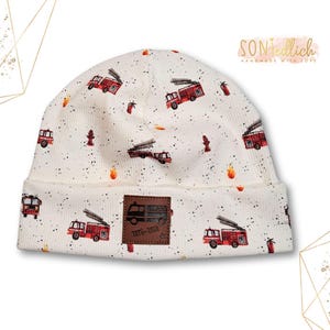 Könnte beinhalten: Weiße Mütze mit einem roten Feuerwehrauto-Muster und einem braunen Leder-Patch mit der Aufschrift "Date-A-Date".