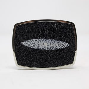 May include: A silver belt buckle with a black and white stingray skin design.