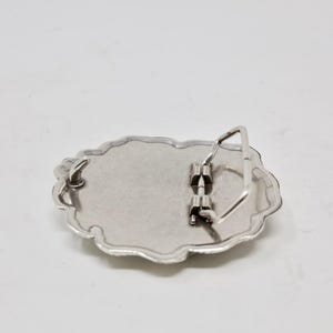 Puede incluir: Hebilla de cintur&oacute;n de metal plateado con forma ovalada y borde festoneado decorativo. La parte posterior de la hebilla presenta un mecanismo de barra y pasador para sujetar a un cintur&oacute;n. La hebilla est&aacute; dise&ntilde;ada para ser duradera y funcional.
