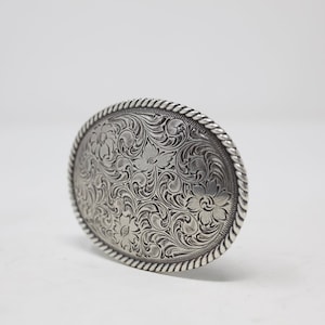 May include: Silver belt buckle with an intricate floral design.