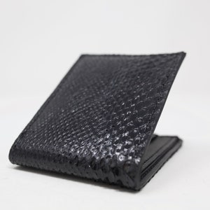 Peut inclure: Un portefeuille en cuir noir avec un motif textur&eacute; en peau de serpent.