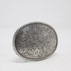 May include: Silver belt buckle with an intricate floral design.