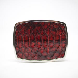 May include: A silver belt buckle with a red snakeskin pattern.