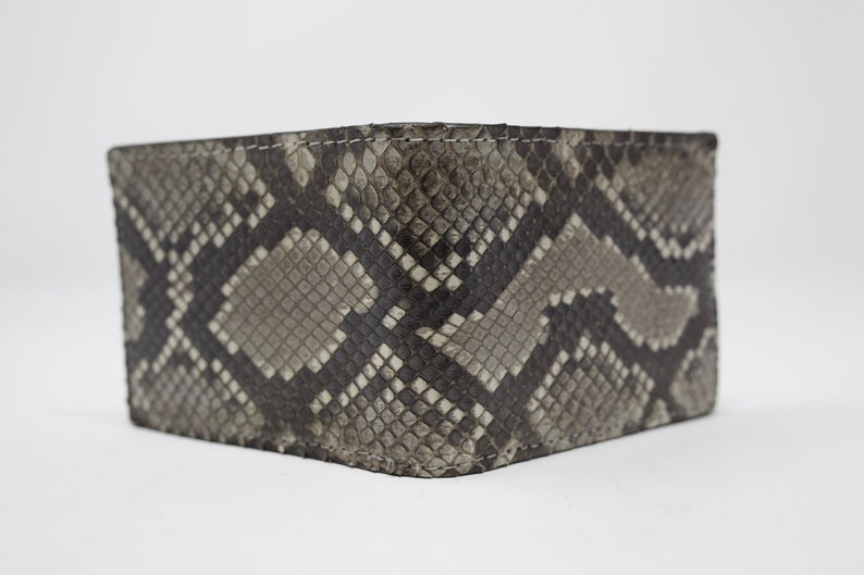 Peut inclure: Un portefeuille en cuir de serpent gris et noir avec un motif textur&eacute;.