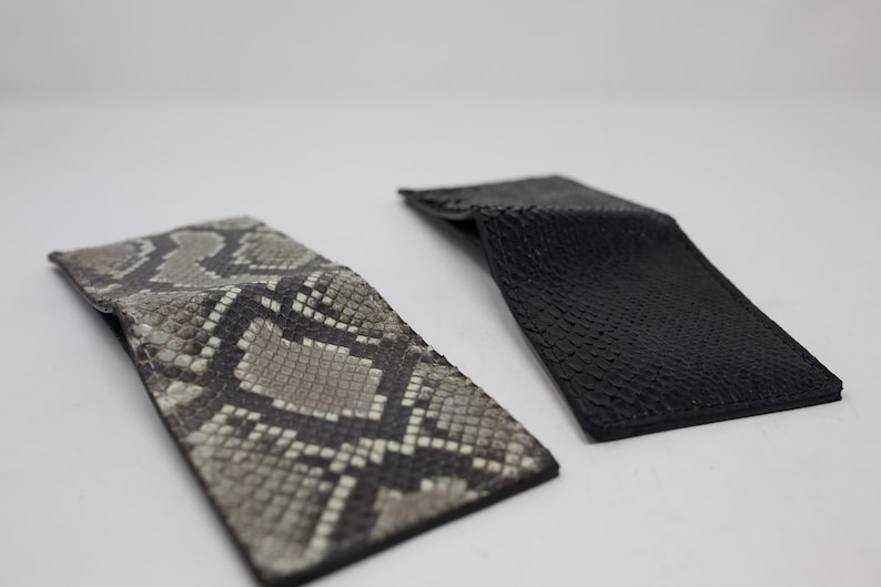 Peut inclure: Deux portefeuilles en cuir, un noir et un autre &agrave; motif de peau de serpent.