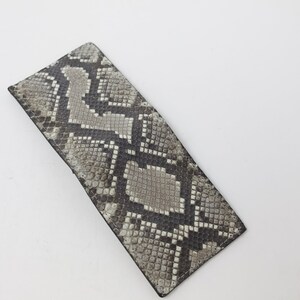 Peut inclure: Un portefeuille en cuir de serpent gris et noir avec un motif textur&eacute;.