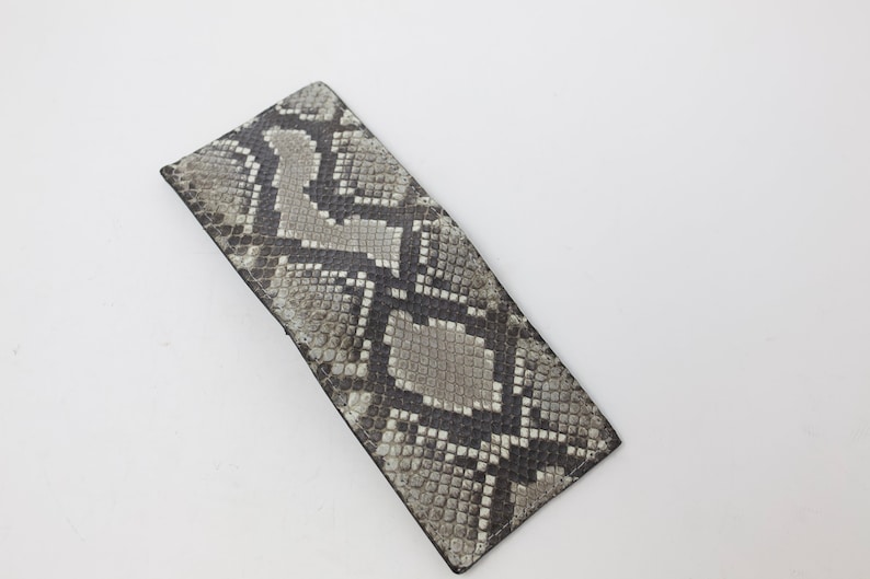 Peut inclure: Un portefeuille en cuir de serpent gris et noir avec un motif textur&eacute;.