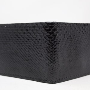 Peut inclure: Un portefeuille en cuir noir avec un motif en peau de serpent.