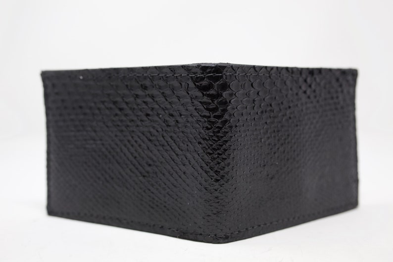 Peut inclure: Un portefeuille en cuir noir avec un motif en peau de serpent.